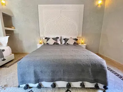 a bedroom with a large bed with a gray blanket at Riad Jolie in Marrakech