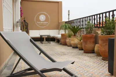 a white chair sitting on a balcony with potted plants at DAR NOUONSA in Marrakech