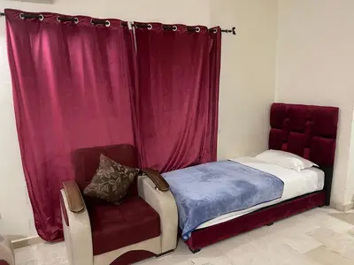 a bedroom with a bed and a red curtain and a chair at Appartement 16 2èm étage ( POUR FAMILLE ) in Marrakech