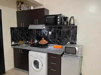 a kitchen with a washing machine and a microwave at Appartement 18 3èm étage avec balcon ( POUR FAMILLE ) in Marrakech