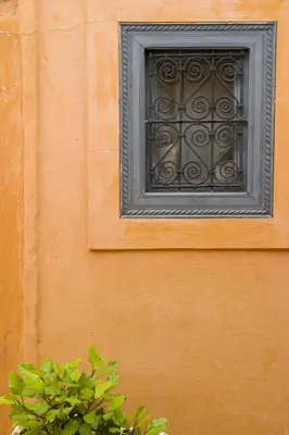 a window on the side of a orange wall with a plant at Dar Touyir in Marrakech