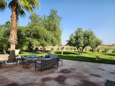 a patio with a couch and chairs and a palm tree at Villa de rêve à Marrakech in Marrakech