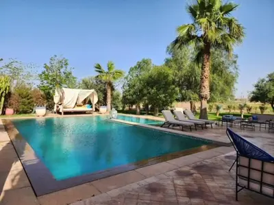 a swimming pool with chairs and palm trees at Villa de rêve à Marrakech in Marrakech
