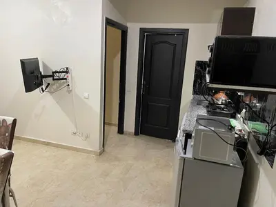 a room with a black door and a television on a counter at Appartement 30 au 5 ème étage avec balcon ( POUR FAMILLE ) in Marrakech