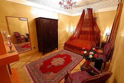 a room with a bedroom with a bed and a chair at Riad Mille Et Une Nuits in Marrakech