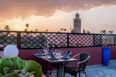 a table and chairs on a balcony with a clock tower at Riad Marrakech By Hivernage in Marrakech