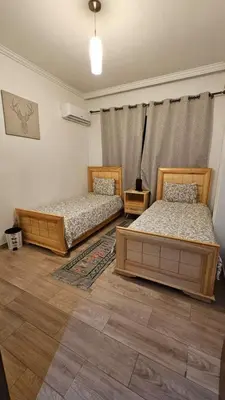 two beds sitting in a room with wooden floors at Bitty Apartment in Marrakech