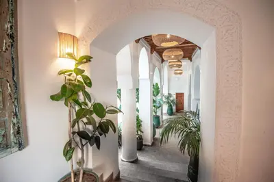 a hallway with white columns and a hallway with plants at Riad Palais Calipau in Marrakech