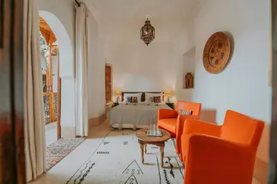 a bedroom with a bed with orange chairs and a table at Riad Djebel in Marrakech