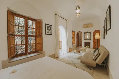 a bedroom with a bed and a couch and windows at Riad Djebel in Marrakech