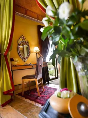 a living room with a chair and a mirror at Pavillon du Golf - Palmeraie suites in Marrakech