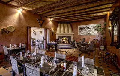 a restaurant with tables and chairs and a fireplace at Hotel Kasbah Le Mirage & Spa in Marrakech