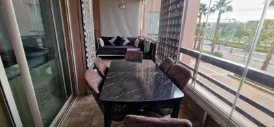 a table and chairs in a room with a balcony at Magnifique appartement à Riad Garden in Marrakech
