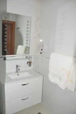 a white bathroom with a sink and a mirror at Magnifique appartement à Riad Garden in Marrakech