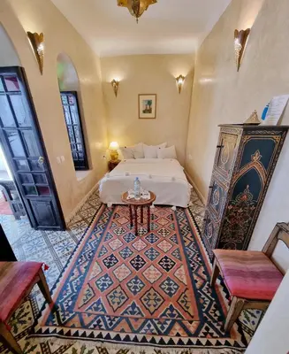 a bedroom with a bed and a table and chairs at Riad Adriana in Marrakech