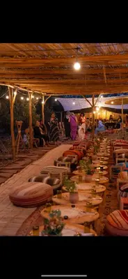 a long line of tables in a tent with people at La Ferme des Tipis Marrakech in Marrakech