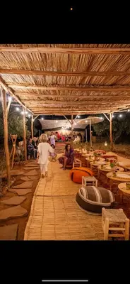a group of people walking through a pavilion with tables at La Ferme des Tipis Marrakech in Marrakech
