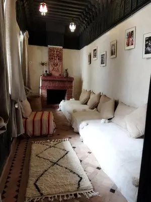 a living room with white pillows and a fireplace at Riad Dowaya in Marrakech