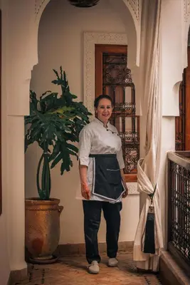 a woman standing in a hallway with a plant at Riad Dar Beldia and Spa in Marrakech