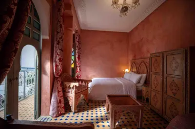 a bedroom with a bed and a table and a window at Riad Zinoun & Spa 11 Rooms in Marrakech
