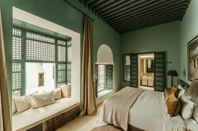 a bedroom with green walls and a bed and windows at Ryad Dyor in Marrakech