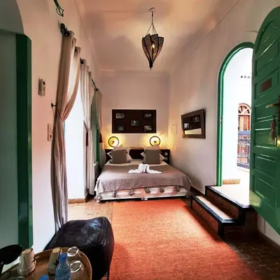 a bedroom with a bed and two large windows at Riad El Grably in Marrakech