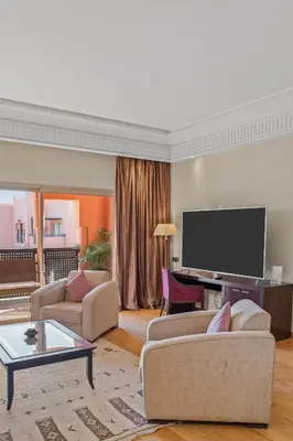 a living room with two couches and a flat screen tv at Kenzi Menara Palace & Resort in Marrakech