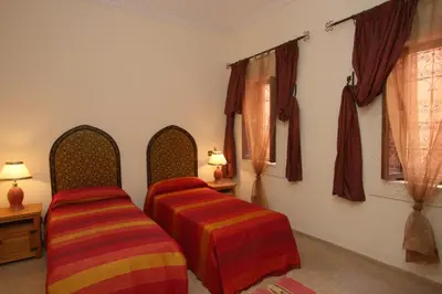 two beds sitting in a room with curtains at Riad petit Karmela in Marrakech