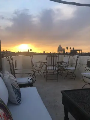a patio with chairs and tables and a sunset at Riad Karmela in Marrakech