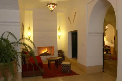 a living room with a fireplace and a couch and a table at Riad Karmela in Marrakech