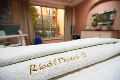 a bed with a white blanket with the word raja madurai on it at Riad Mazal in Marrakech