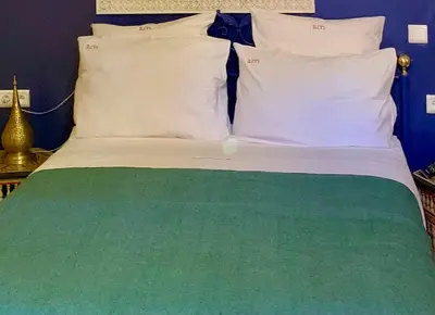 a bed with white and green sheets and pillows at Riad Mazal in Marrakech