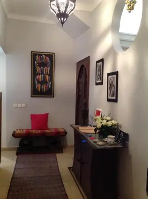 a room with a bench and a table with a vase of flowers at Riad Nafis in Marrakech