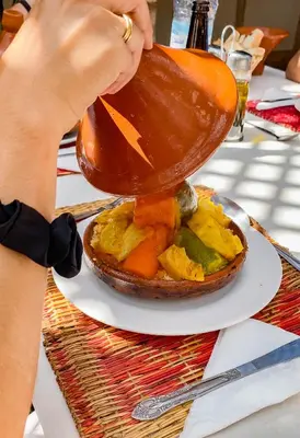 a person is pouring sauce onto a plate of food at Equity Point Marrakech in Marrakech