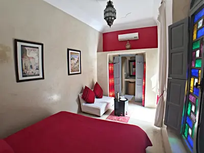 a living room with a red bed and a couch at Riad Bel Haj in Marrakech
