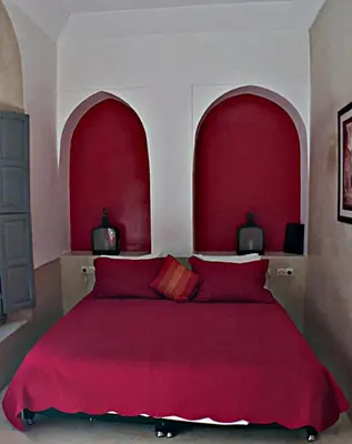 a bedroom with a large red bed with red pillows at Riad Bel Haj in Marrakech