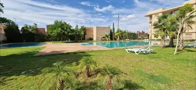 a swimming pool with two white chairs in a yard at COSY APPART avec 2 piscines, 2 CH, 2 SDB Marrakech in Marrakech