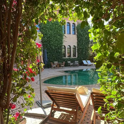 a swimming pool with two chairs and a building at Al Fassia Aguedal in Marrakech