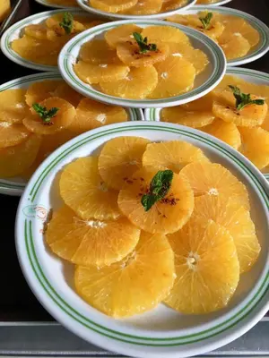 a pile of orange slices on plates on a table at Al Fassia Aguedal in Marrakech