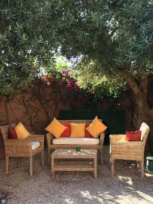 a couch and two chairs under a tree at Al Fassia Aguedal in Marrakech