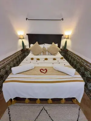 a bedroom with a large bed with white sheets and pillows at Riad Al Karama in Marrakech