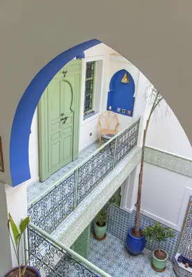 a staircase in a house with a blue door and a plant at Riad Med Agorà in Marrakech