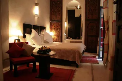 a bedroom with a bed and a table and a chair at Riad Diana in Marrakech