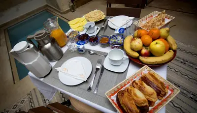 a table with a bunch of food and a bowl of fruit at Riad Dar Zaya in Marrakech