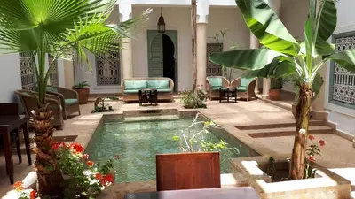 a pool in the middle of a living room with palm trees at Riad Les Hibiscus in Marrakech