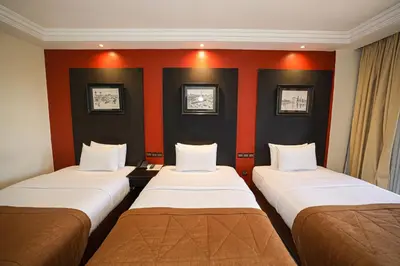 three beds in a room with orange and black walls at El Andalous Lounge & Spa Hotel in Marrakech