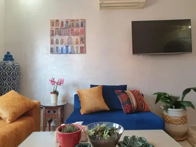 a living room with a blue couch and a tv at Bel appartement moderne au cœur de guelize in Marrakech