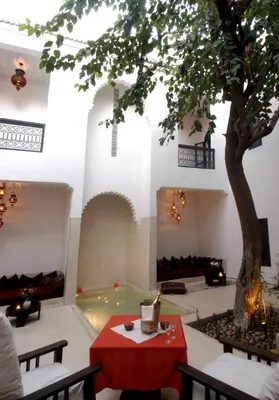 a room with a tree and a table and chairs at Riad Davia in Marrakech