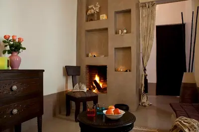 a living room with a fireplace and a table with a bowl of fruit at Riad Davia in Marrakech