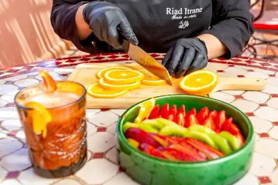 a person cutting up vegetables with a knife on a cutting board at Riad Itrane in Marrakech